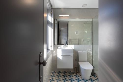 a bathroom with a toilet and a sink and a mirror at Cedofeita's Blue House in Porto