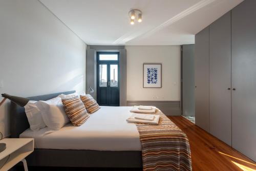 a bedroom with a large bed with white sheets and pillows at Cedofeita's Blue House in Porto