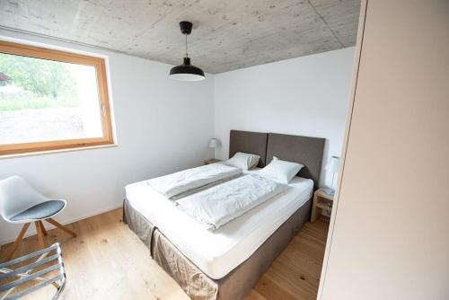 ein Schlafzimmer mit einem Bett, einem Stuhl und einem Fenster in der Unterkunft Casa Acletta - die Ferienwohnung in Valbella in Valbella