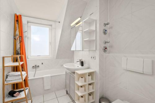 Baño blanco con lavabo y bañera en CASSEL LOFTS - Idyllische Maisonette-Wohnungen nähe Bergpark Wilhelmshöhe, en Kassel