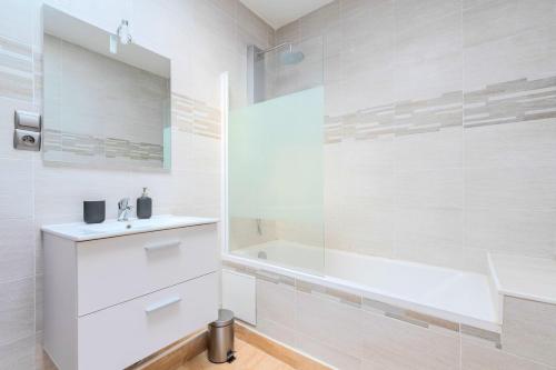 La salle de bains blanche est pourvue d'un lavabo et d'une baignoire. dans l'établissement Roubaix - Beautiful 4 bedrooms house with terrace!, à Roubaix