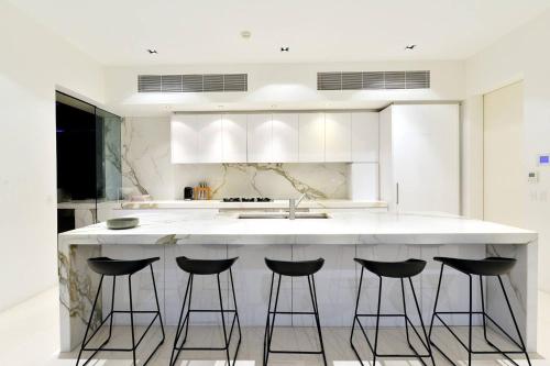 a kitchen with a island with four bar stools at 61 Murphy Street - Luxury Holiday Home in Port Douglas