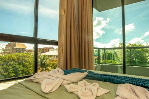 a bed with towels on it in front of a window at Apto a 150m da praia, Rooftop com piscina & sauna em Porto de Galinhas in Porto De Galinhas