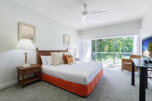 Tropical Resort-style Living on Mirage Golf Course في ميناء دوغلاس: غرفة نوم بسرير ومكتب ونافذة