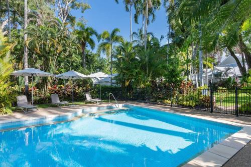 a swimming pool with palm trees and umbrellas at Tropical Resort-style Living on Mirage Golf Course in Port Douglas