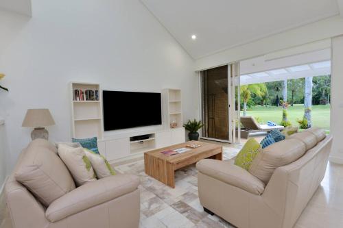 a living room with two couches and a flat screen tv at Fairway Vistas - A Group Escape at Mirage Resort in Port Douglas