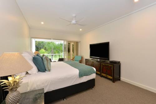 Schlafzimmer mit einem Bett und einem Flachbild-TV in der Unterkunft Fairway Vistas - A Group Escape at Mirage Resort in Port Douglas