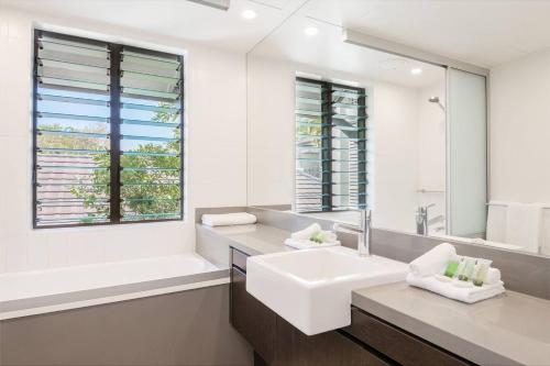 a white bathroom with a sink and a tub and a window at The Oasis at Temple - A Rooftop Resort Retreat in Port Douglas