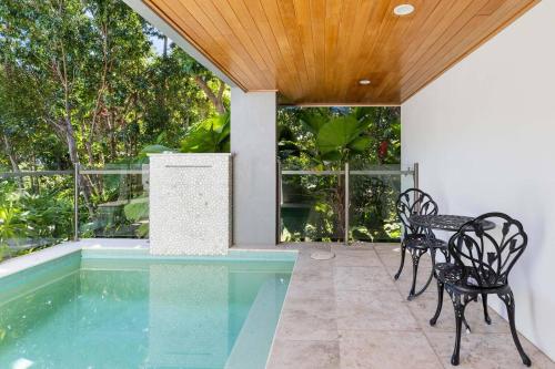 una piscina con dos sillas y una mesa en Villa Mercedes - Poolside Tranquility on Murphy St, en Port Douglas