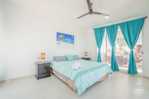 una camera da letto con un letto con tende blu e una finestra di Penthouse Apartments Private Roof Pool 200m to Beach a Chicxulub