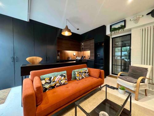 a living room with an orange couch and a kitchen at Ground floor central apartment in Kingsbridge