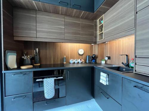 a kitchen with dark blue cabinets and wooden walls at Ground floor central apartment in Kingsbridge