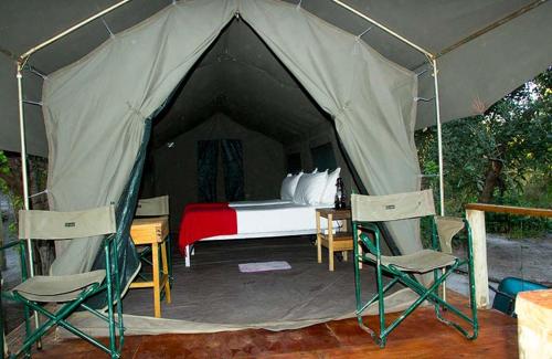 a tent with a bed and two chairs in it at Candies Vacation Cottage Khwai in Khwai