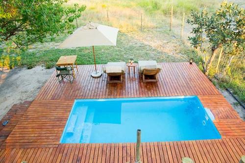 Khwai的住宿－Candies Vacation Cottage Khwai，一个带桌子和遮阳伞的游泳池