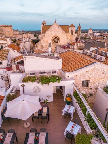 an outdoor patio with tables and chairs and an umbrella at Hotel Corte Altavilla in Conversano