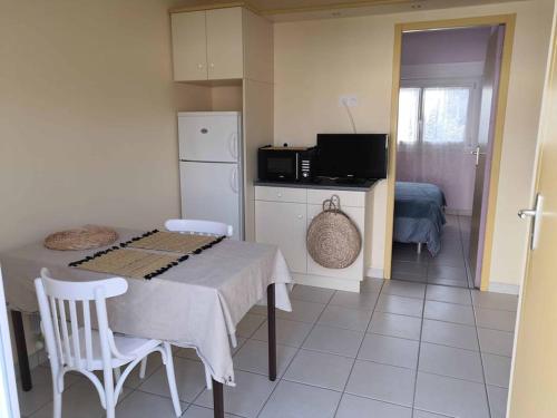 une cuisine avec une table avec des chaises et un réfrigérateur dans l'établissement Appartement 27 Groix, à La Bernerie-en-Retz