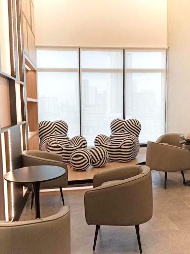 a room with chairs and a table and a large window at Urban Suites 3 Rooms, Cat Theme & Romantic in Jelutong