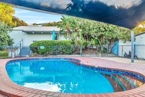 a swimming pool with a brick walkway around it at Blue Cabin Bliss at Aldinga Bay Holiday Village in Aldinga Beach