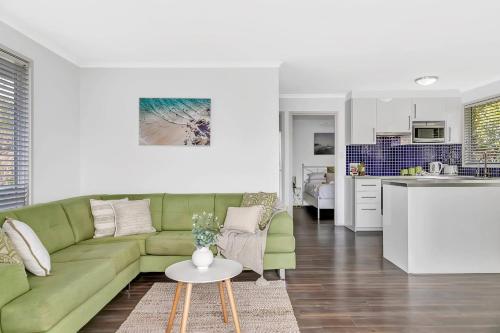 a living room with a green couch and a kitchen at Blue Cabin Bliss at Aldinga Bay Holiday Village in Aldinga Beach