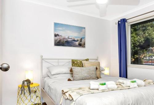 a white bedroom with a large bed and a window at Blue Cabin Bliss at Aldinga Bay Holiday Village in Aldinga Beach