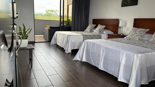 a hotel room with two beds and a balcony at Arenal Monara in Fortuna