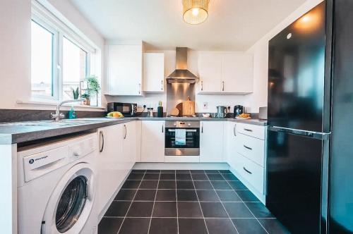 a kitchen with white cabinets and a black refrigerator at Templer Mill by Solace Stays 2 Shower Rooms in Newport