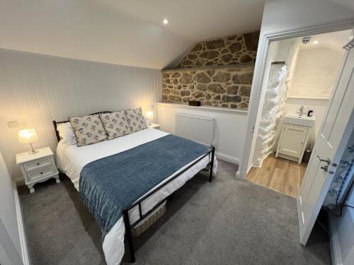 um pequeno quarto com uma cama e uma parede de pedra em The White House at The Tinners Arms em St. Ives