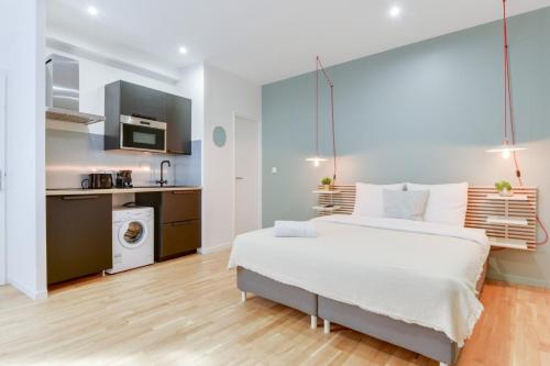 une chambre avec un grand lit blanc et une cuisine dans l'établissement Studio near train station, à Lille