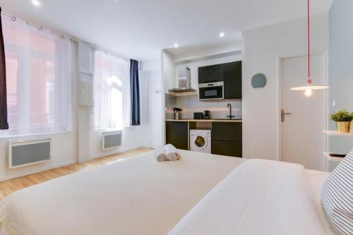 une chambre blanche avec un grand lit blanc et une cuisine dans l'établissement Studio near train station, à Lille
