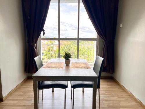 a dining room table with chairs and a large window at HillLand Suites in Ayer Keroh
