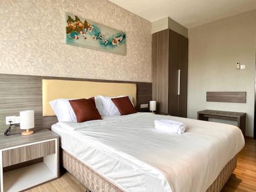 a bedroom with a large bed with white sheets at HillLand Suites in Ayer Keroh