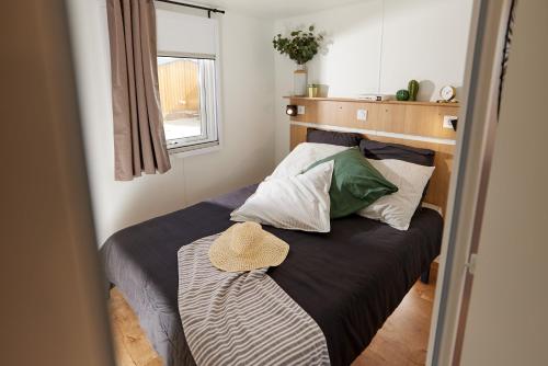 een kleine slaapkamer met een bed met een hoed erop bij Camping Mas Llinas in Le Boulou