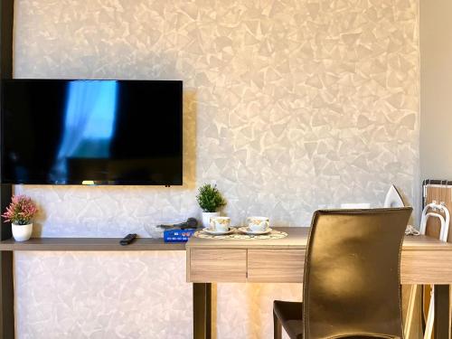 a television on a wall with a table and a chair at HillLand Suites in Ayer Keroh