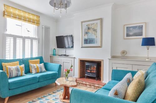 a living room with blue couches and a fireplace at Spacious coastal cottage close to beach - Bailey Cottage in Deal