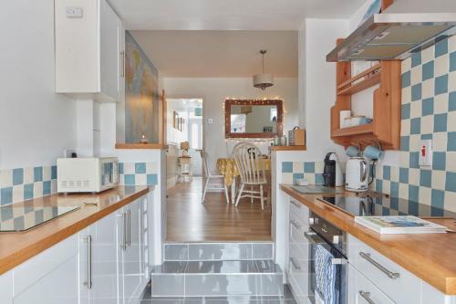 uma cozinha com armários brancos e azulejos azuis e brancos em Spacious coastal cottage close to beach - Bailey Cottage em Deal