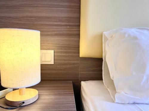 a lamp sitting on a table next to a bed at HillLand Suites in Ayer Keroh