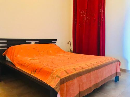 un lit avec une couette orange et un rideau rouge dans l'établissement Appartement La Résidence II - 21 LUMIO, à Lumio