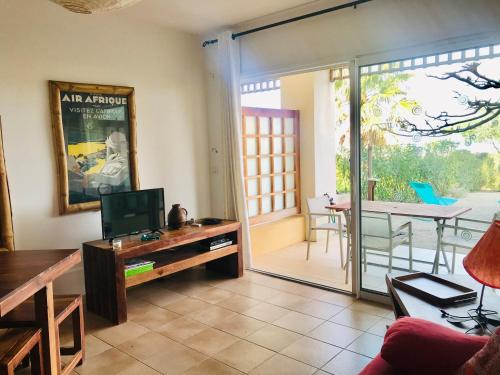 - un salon avec une télévision et une porte coulissante en verre dans l'établissement Appartement La Résidence II - 21 LUMIO, à Lumio