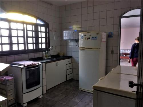 een keuken met witte apparatuur en een persoon in een raam bij Casa com piscina in Bertioga