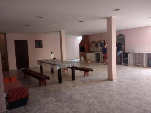 Habitación grande con mesa y bancos. en Casa com piscina en Bertioga