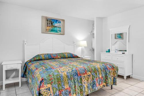 a white bedroom with a bed with a colorful bedspread at Blackfin Resort and Marina in Marathon
