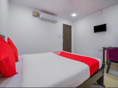 a white bed with red pillows in a bedroom at THE METRO INTERNATIONAL HOTEL in Hyderabad