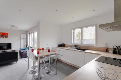 d'une cuisine et d'un salon avec des placards blancs et une table. dans l'établissement Rosamaris - Maison pour 8 avec jardin, à Saint-Malo