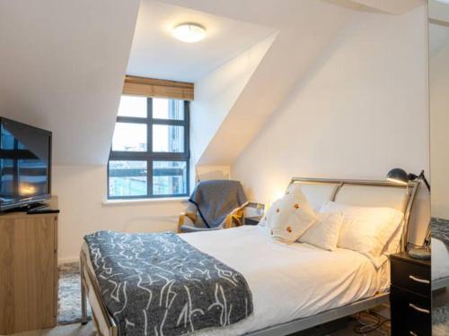 een slaapkamer met een bed met een stoel en een televisie bij Pass the Keys MCR City Centre Apartment with view in Manchester