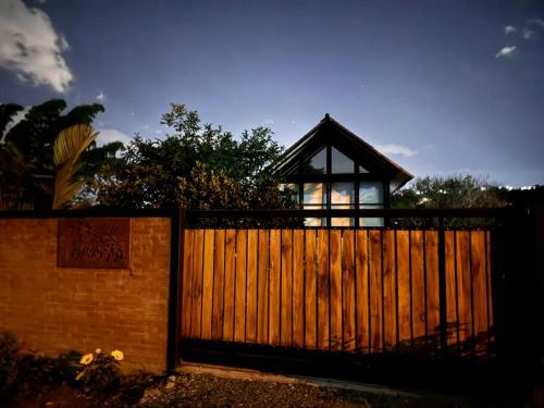 a wooden fence with a house behind it at El refugio del Guayacán in Manizales
