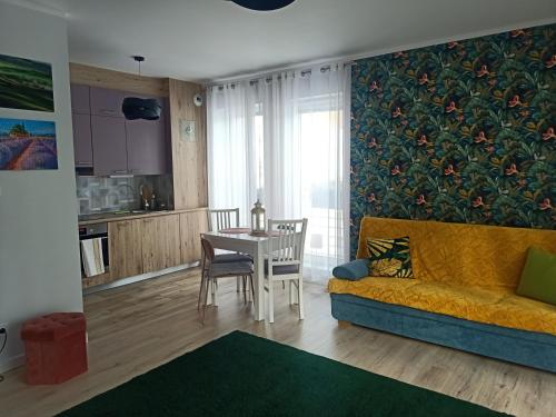 uma sala de estar com um sofá amarelo e uma mesa em Apartament KLARA em Rumia