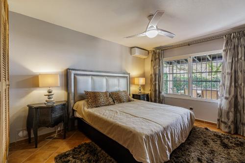 a bedroom with a bed with a ceiling fan and a window at Charming private villa in Marbella in Marbella