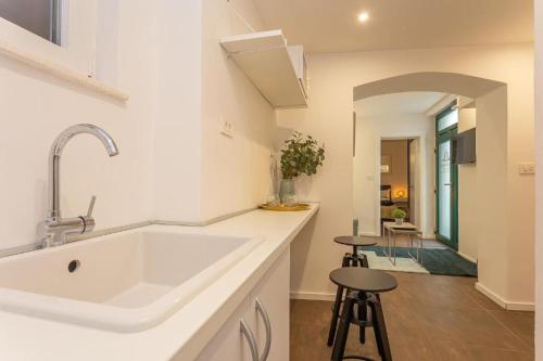 a white kitchen with a sink and two stools at X Boutique Marinac Studio Apartments & Rooms in Šibenik