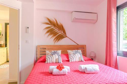een slaapkamer met een roze bed en 2 witte handdoeken bij Le planteur in Rivière-Pilote