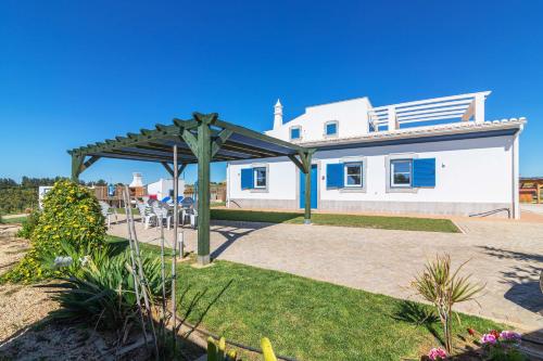a white house with a pergola in the yard at Quinta da Bornacha - Casa A in Vila Nova De Cacela